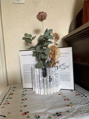 Vase contenant réalisé en pliant les pages d'un livre et contenant des fleurs séchées